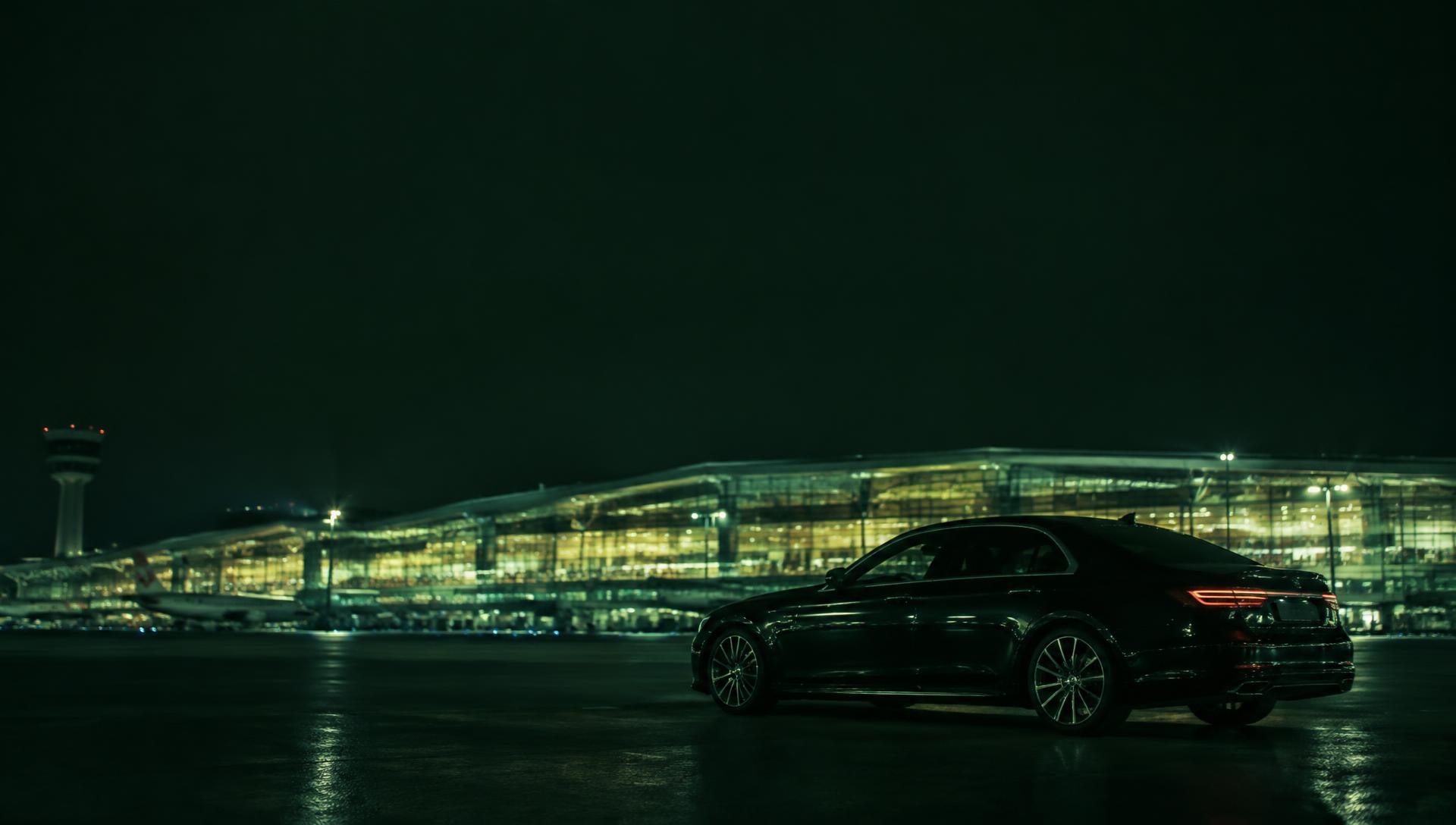 Private car waiting at an illuminated airport terminal
